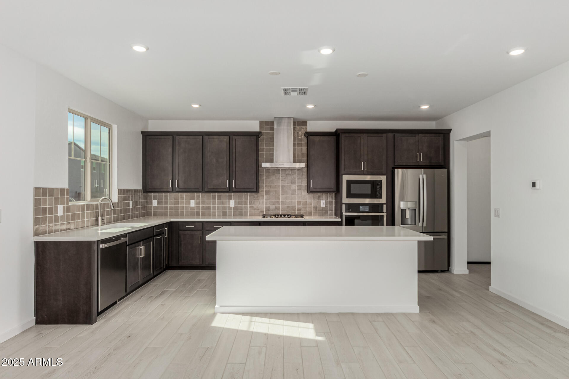 2474 West Rowel Road Phoenix, AZ 85085 - Photo 8 of 38 a large kitchen with stainless steel appliances kitchen island granite countertop a stove a sink dishwasher and a refrigerator with wooden floor