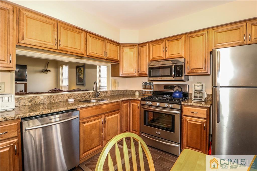 306 Maplecrest Road, Unit 306 Edison, NJ 08820 - Photo 8 of 25 a kitchen with stainless steel appliances granite countertop a stove top oven a refrigerator and a sink
