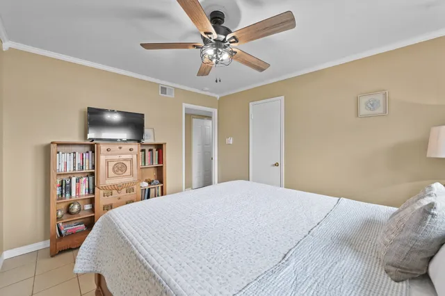 a bedroom with a bed a flat screen tv and a chandelier
