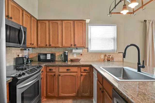 a kitchen with stainless steel appliances granite countertop a stove a sink and a microwave