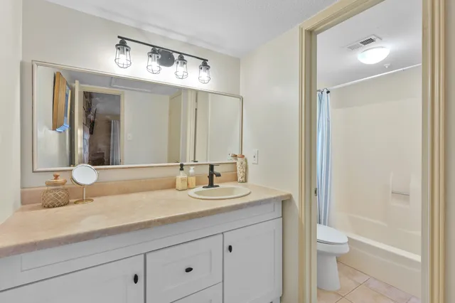 a bathroom with a granite countertop sink a toilet and a large mirror