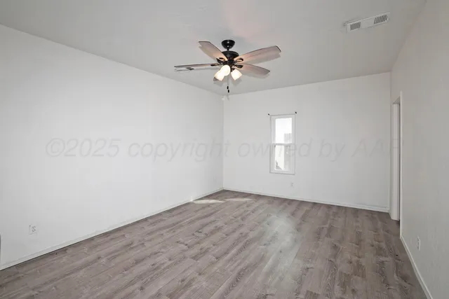 an empty room with wooden floor closet and fan