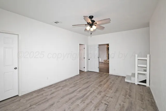 a view of empty room with wooden floor and ceiling fan