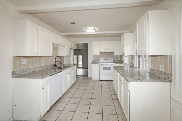 a large kitchen with granite countertop a sink and cabinets