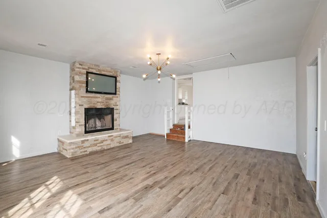 an empty room with wooden floor fireplace and a window
