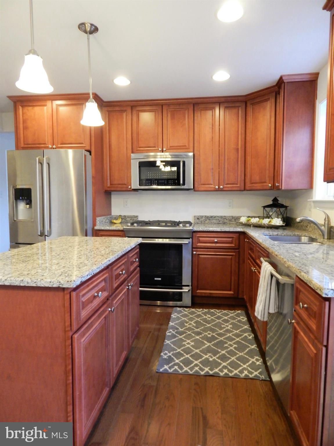8254 Quarterfield Road Severn, MD 21144 - Photo 12 of 30 a kitchen with stainless steel appliances granite countertop a stove a sink dishwasher a refrigerator and a oven with wooden floor