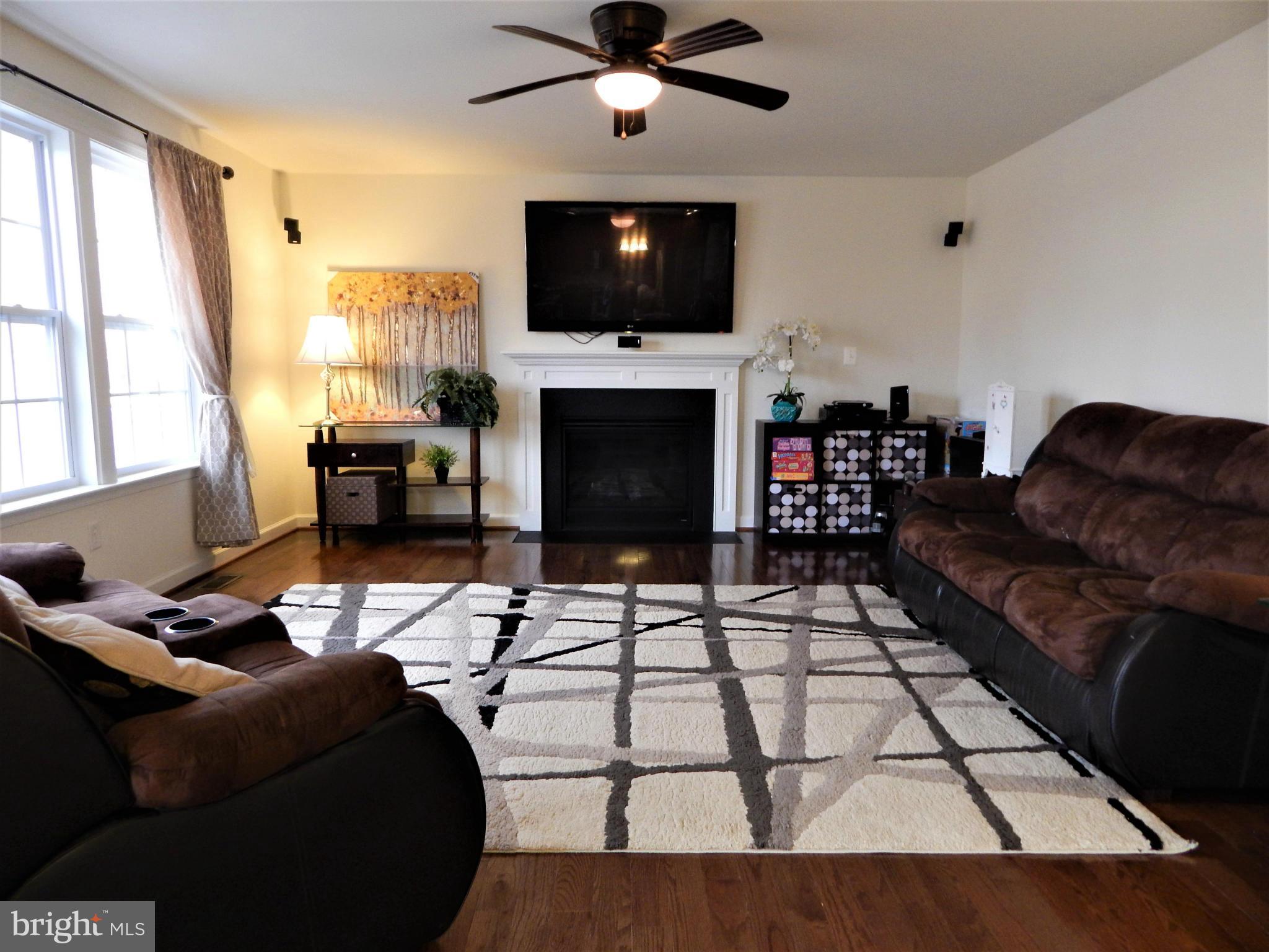 8254 Quarterfield Road Severn, MD 21144 - Photo 13 of 30 a living room with furniture a fireplace and a flat screen tv