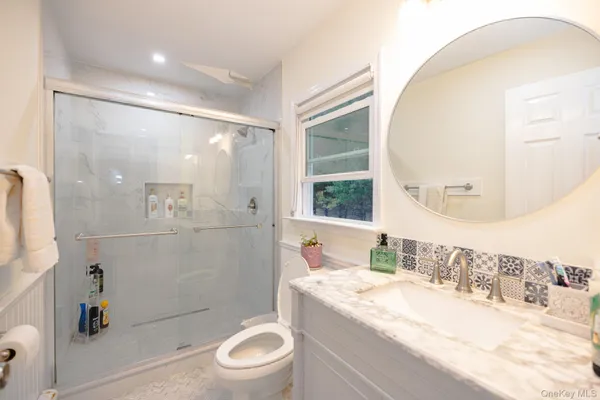 a bathroom with a granite countertop sink a toilet and shower