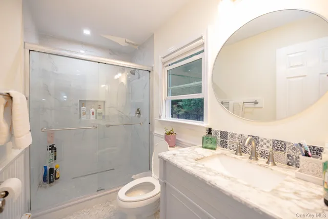 a bathroom with a granite countertop sink a toilet and shower