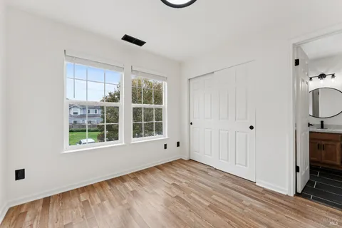 an empty room with wooden floor cabinet and windows