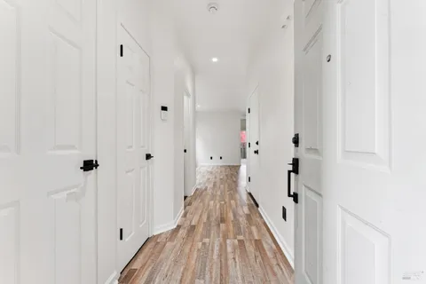 a view of a hallway with wooden floor and a bathroom