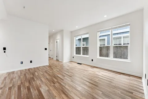 a view of empty room with wooden floor and windows