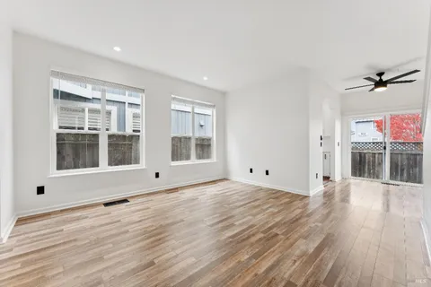 a view of an empty room with a window and wooden floor