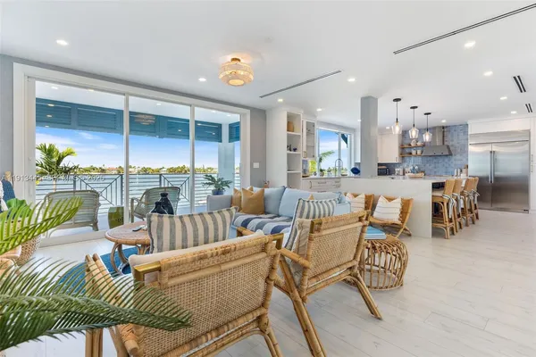 a living room with furniture kitchen view and a large window