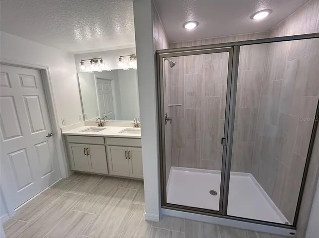 a bathroom with a double vanity sink a toilet a shower and a mirror