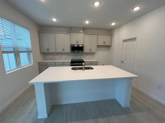 a kitchen with kitchen island sink stove and cabinets