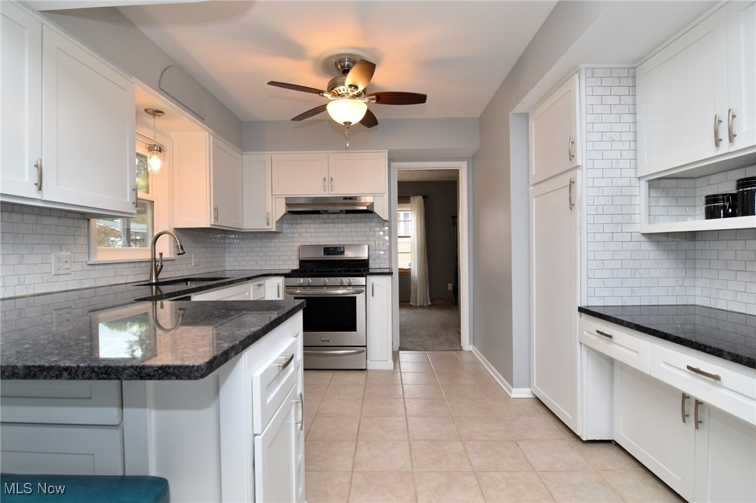 2071 Wyndham Road Akron, OH 44313 - Photo 11 of 42 Kitchen with tasteful backsplash, gas stove, sink, ceramic tile floors, and white cabinetry.