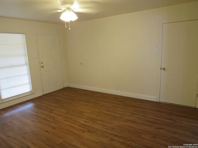 a view of an empty room with wooden floor and a window