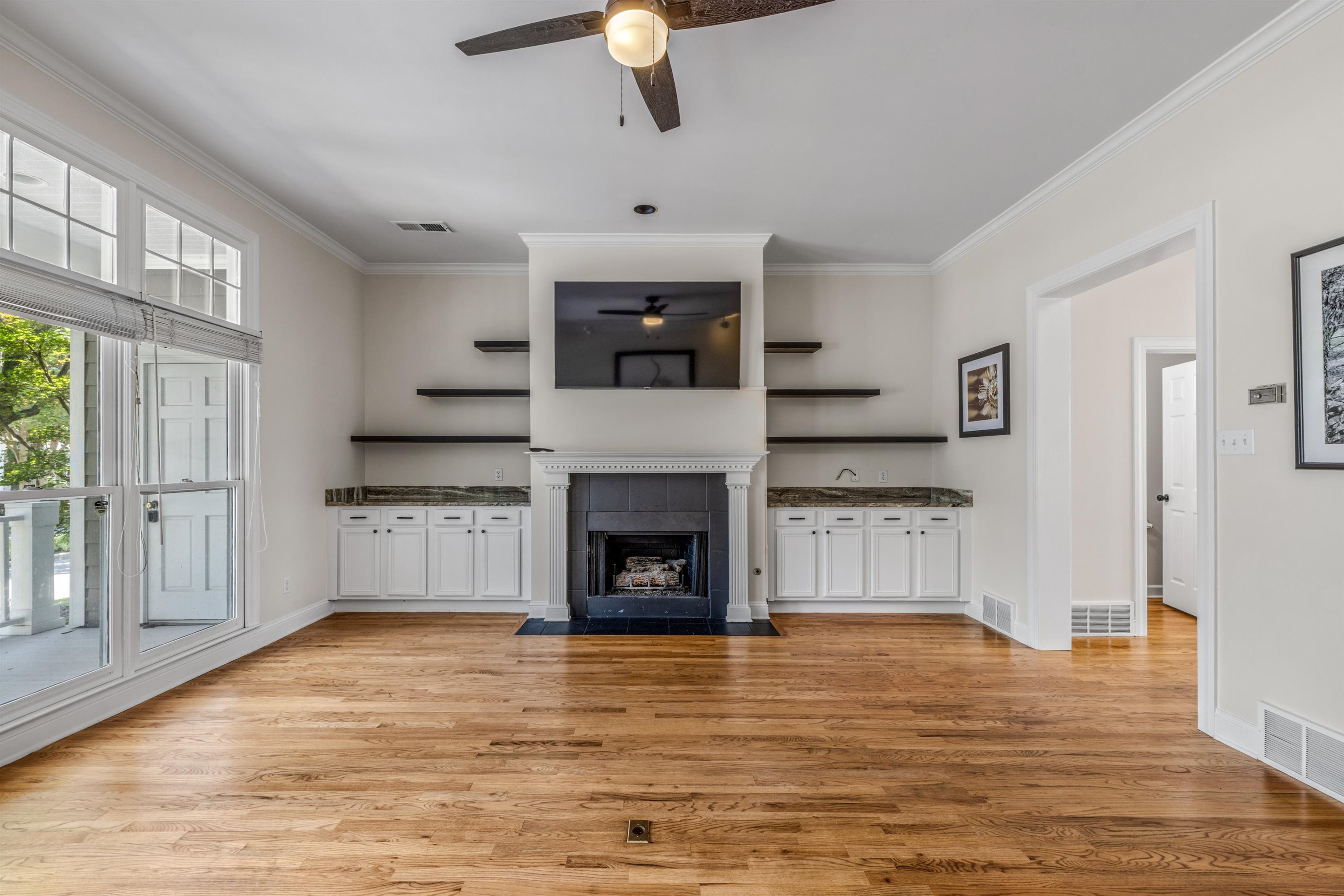 921 Harbor View Drive Memphis, TN 38103 - Photo 21 of 33 Living area featuring wood-finish flooring, a fireplace with a mantel, built-in cabinetry with stone countertops, and shelving