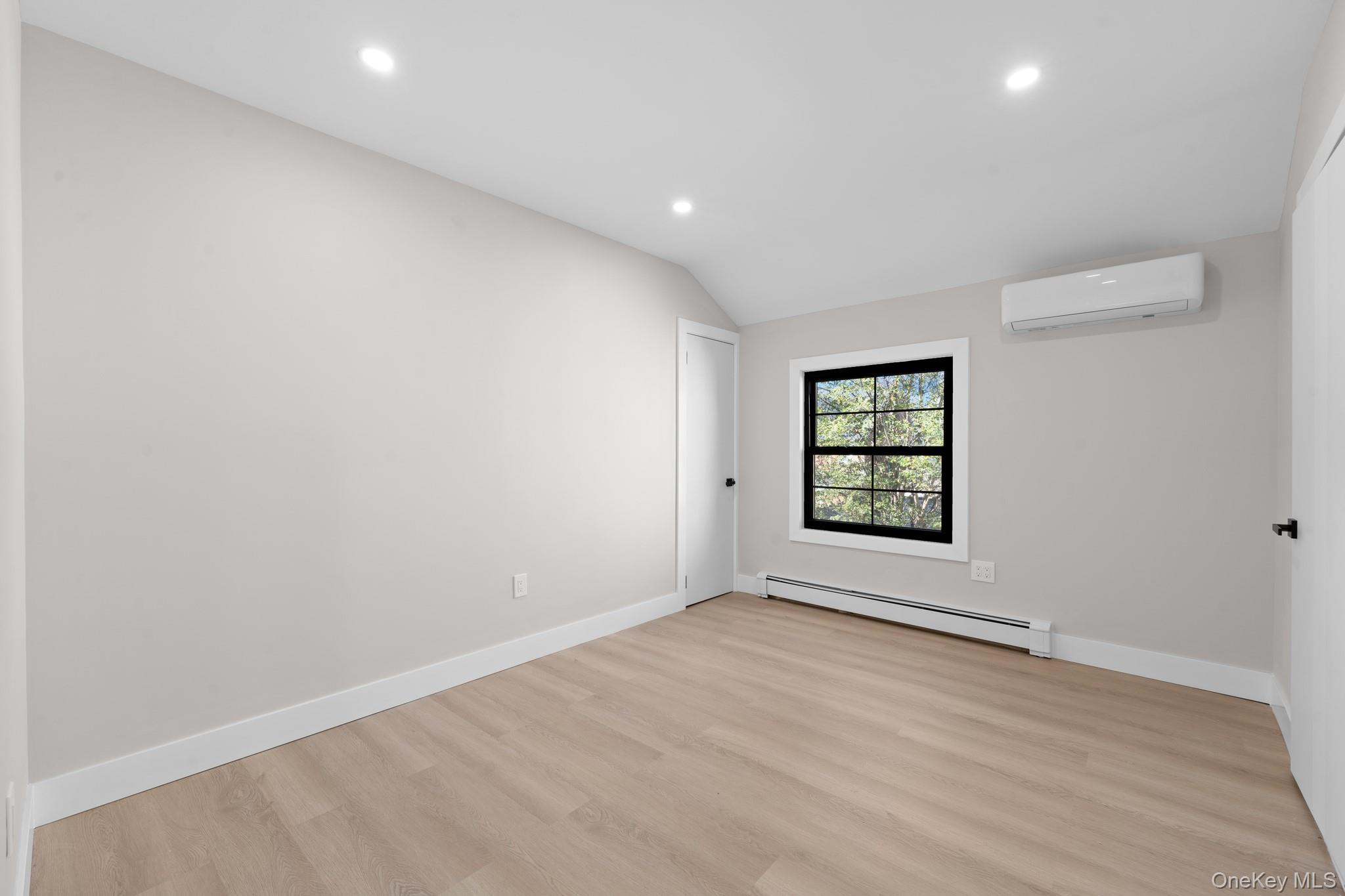 115-16 199th Street Queens, NY 11412 - Photo 14 of 21 Spare room featuring recessed lighting, a baseboard heating unit, light wood-type flooring, vaulted ceiling, and a wall unit AC