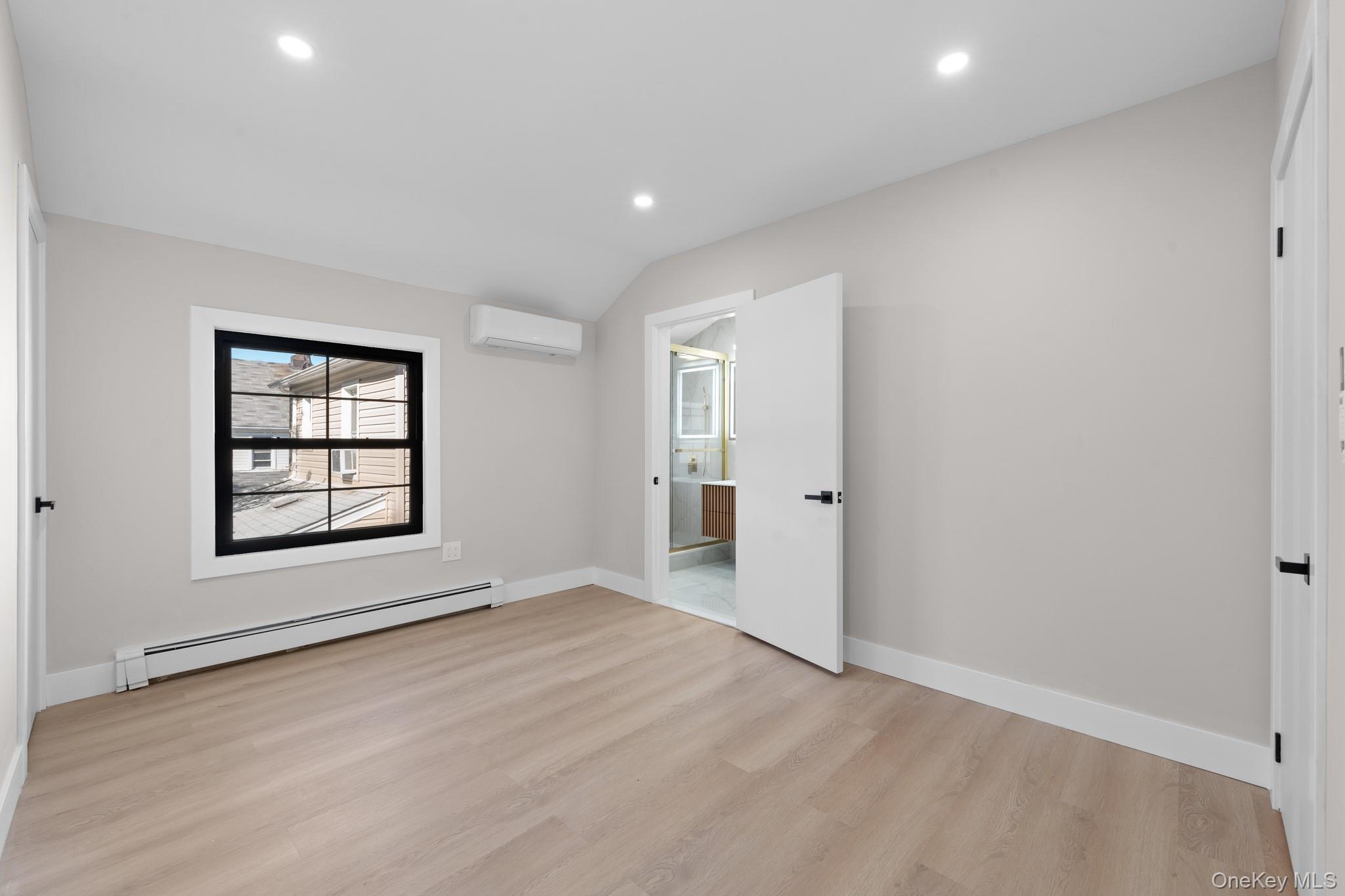 115-16 199th Street Queens, NY 11412 - Photo 15 of 21 Unfurnished bedroom with a baseboard heating unit, light wood-type flooring, recessed lighting, an AC wall unit, and lofted ceiling