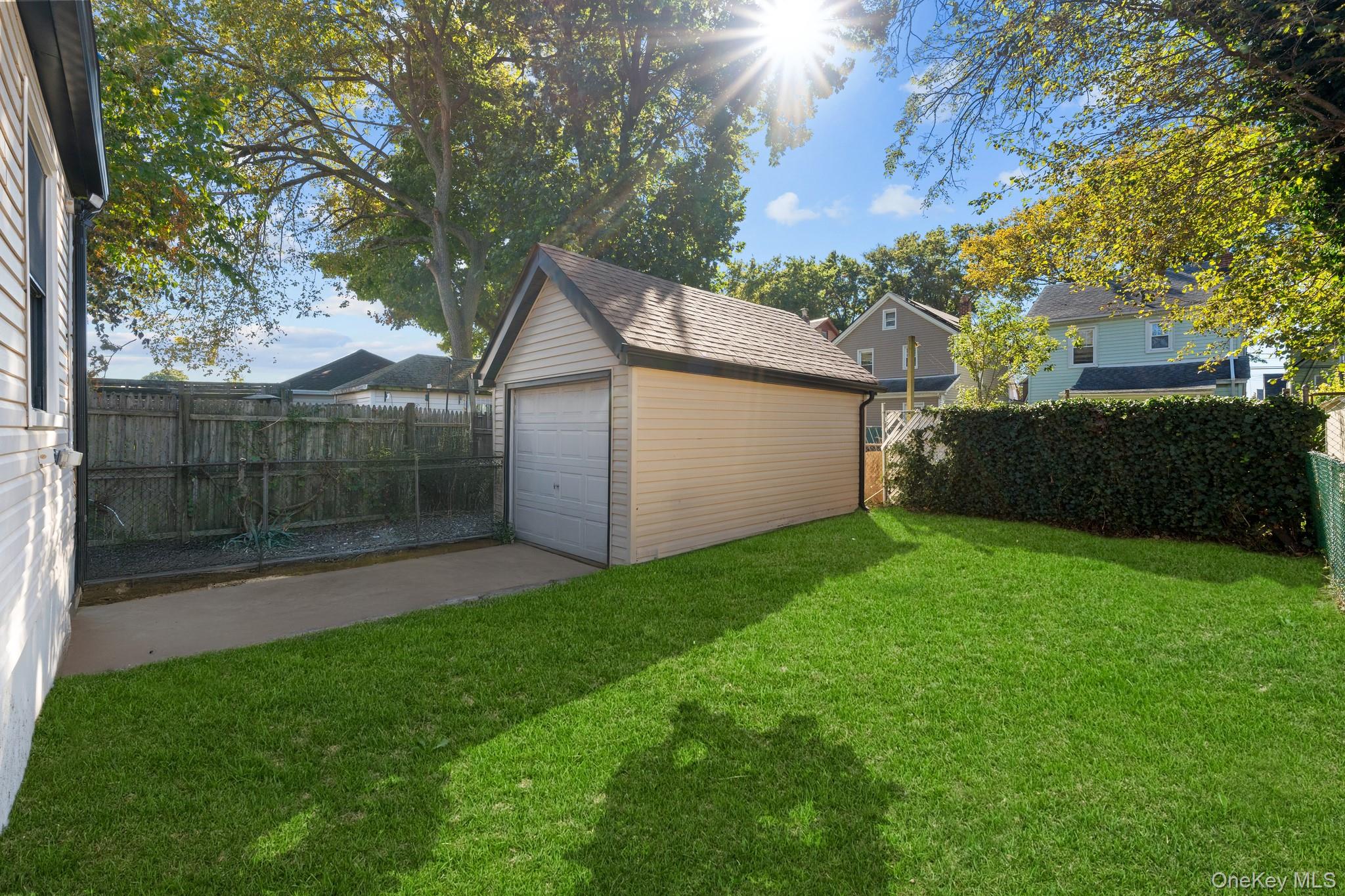 115-16 199th Street Queens, NY 11412 - Photo 17 of 21 Fenced backyard featuring an outdoor structure, a detached garage, and driveway