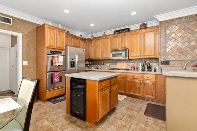 a kitchen with stainless steel appliances granite countertop a stove top oven a sink dishwasher and a refrigerator with wooden cabinets