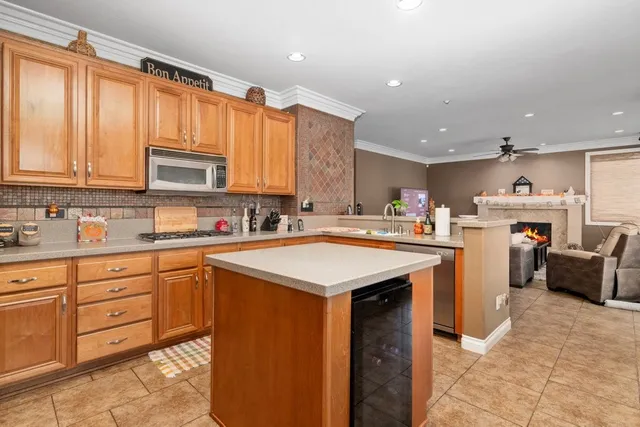 a kitchen with stainless steel appliances kitchen island granite countertop a table chairs sink and cabinets