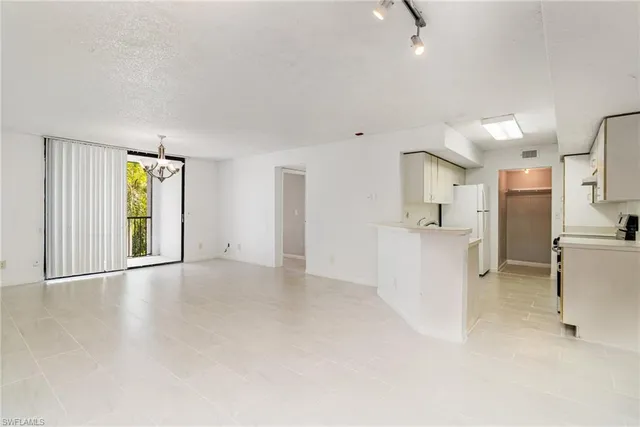 a view of a kitchen with a sink and dishwasher a refrigerator with white cabinets