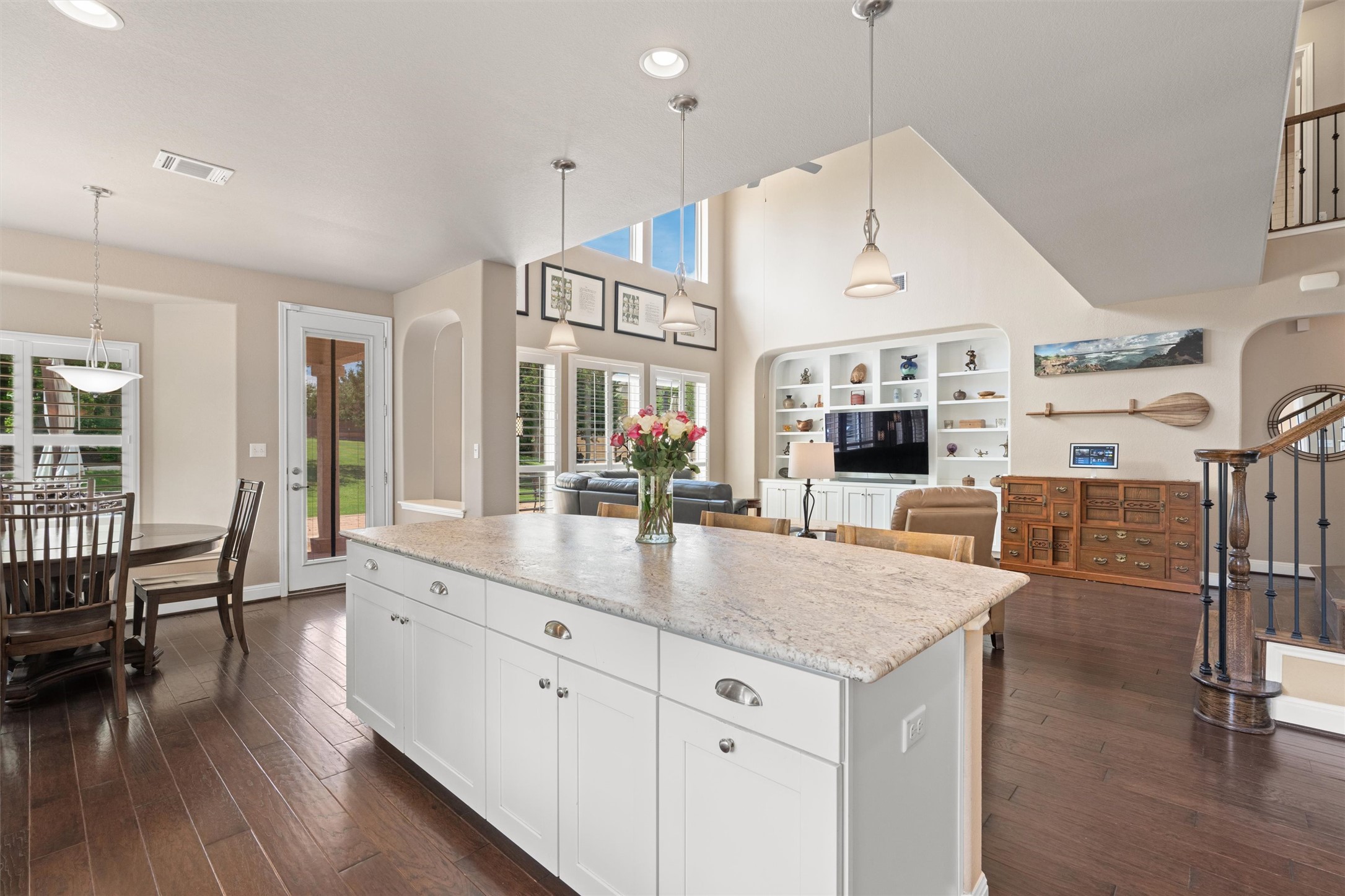 7716 Aria Loop Austin, TX 78736 - Photo 1 of 39 An open-concept living space features an expansive kitchen island, high ceilings, and beautiful hardwood flooring.