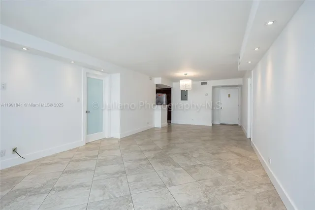 an empty room with chandelier fan and windows