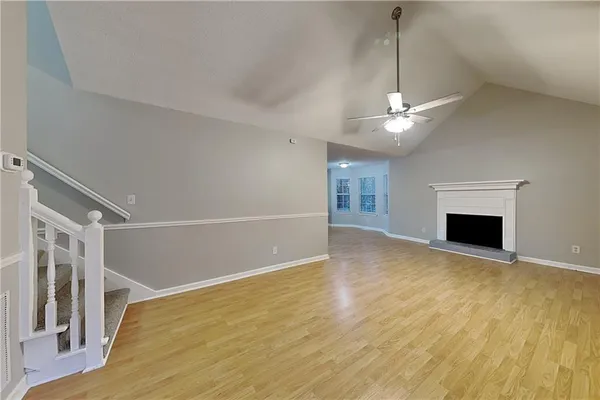 a view of a livingroom with a fireplace a ceiling fan and wooden floor