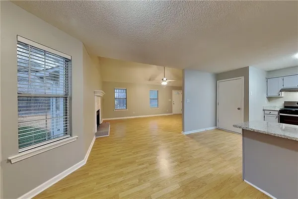 a view of an empty room with window and a kitchen