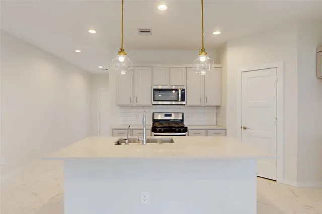 a kitchen with kitchen island a sink stainless steel appliances and white cabinets
