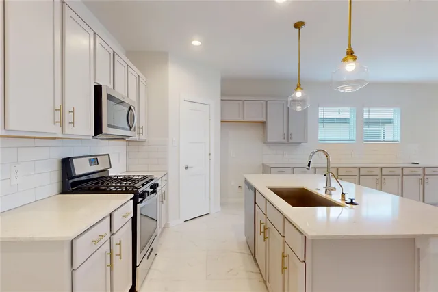 a kitchen that has a sink a stove and a microwave
