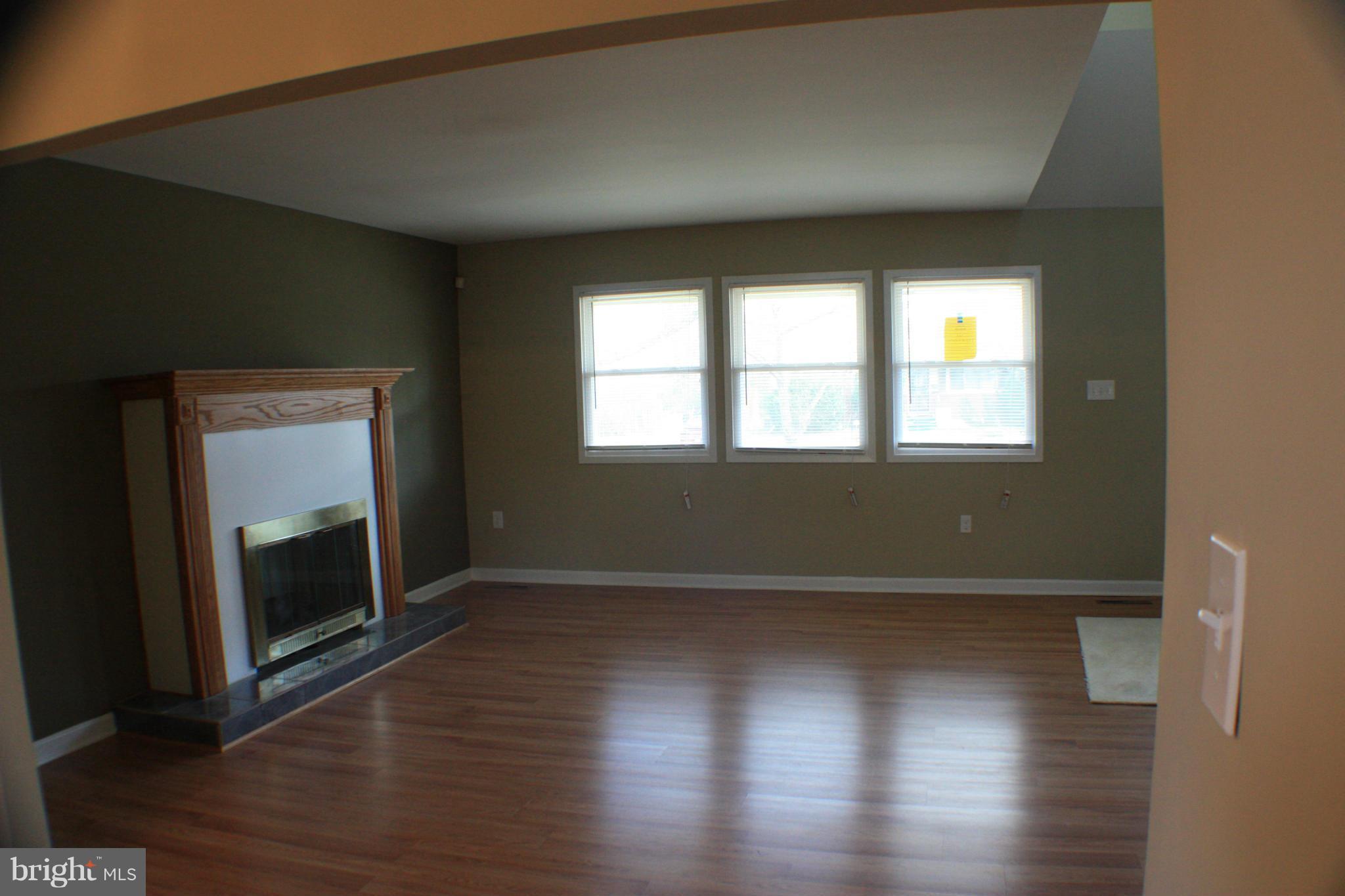 2016 Greengage Road Baltimore, MD 21244 - Photo 3 of 26 an empty room with wooden floor fireplace and windows
