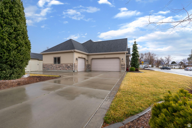 557 South 1470th Street East Springville, UT 84663 - Photo 43 of 46 View of home's exterior with stucco siding, stone siding, a garage, driveway, and a yard