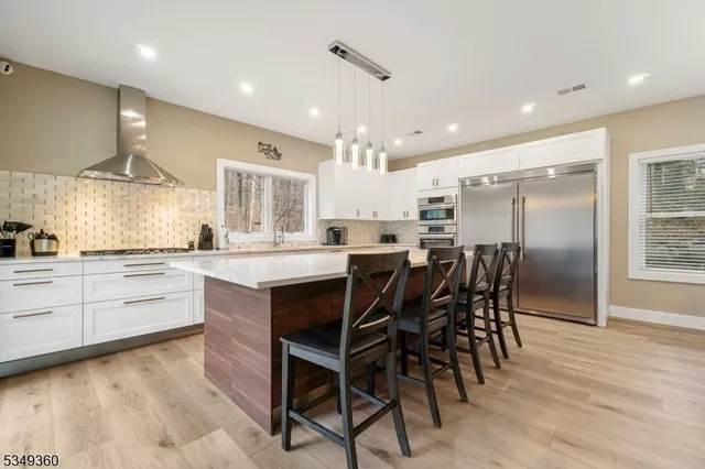 a kitchen with stainless steel appliances kitchen island granite countertop a table chairs sink and cabinets