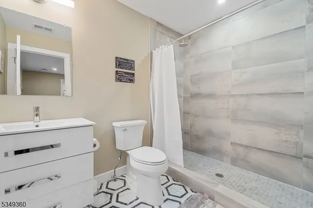 a bathroom with a shower sink vanity mirror and toilet