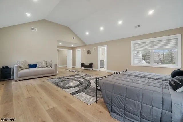 a spacious bedroom with a bed a couch and large window