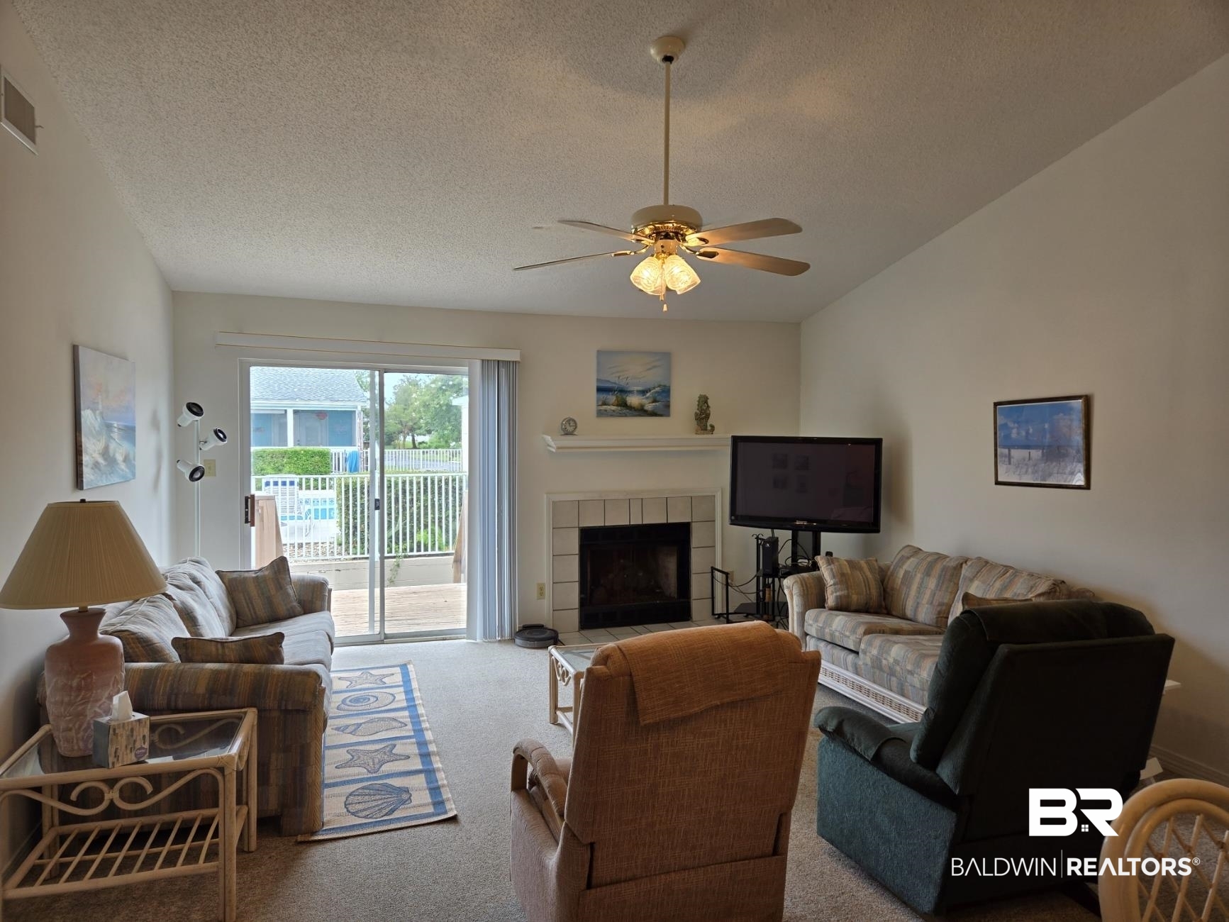 3200 Loop Road, Unit 87 Orange Beach, AL 36561 - Photo 10 of 46 Living room with carpet floors, a textured ceiling, ceiling fan, and a tile fireplace