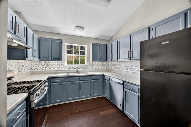 a kitchen with stainless steel appliances granite countertop a refrigerator and a sink