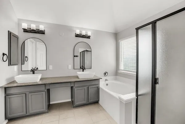 a bathroom with a double vanity sink and mirror with bathtub