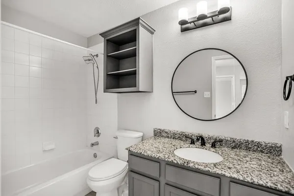 a bathroom with a granite countertop sink a toilet and a mirror