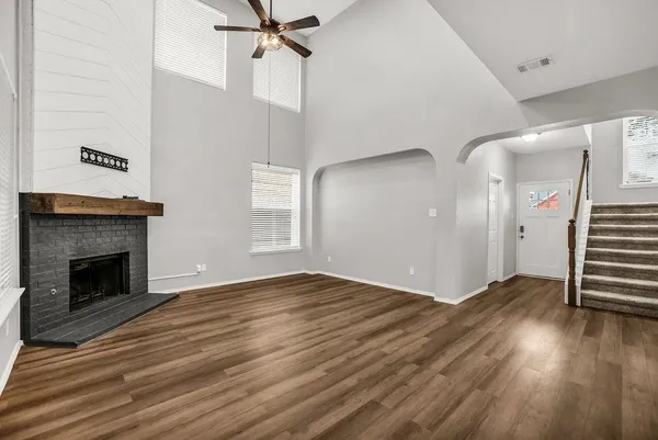an empty room with wooden floor fireplace and windows