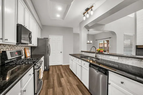 a kitchen with stainless steel appliances a sink dishwasher a stove top oven a refrigerator with island and cabinets