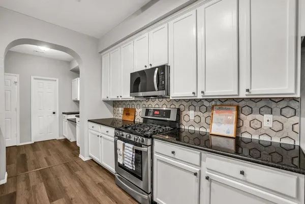 a kitchen with stainless steel appliances granite countertop a stove a sink and a white cabinets