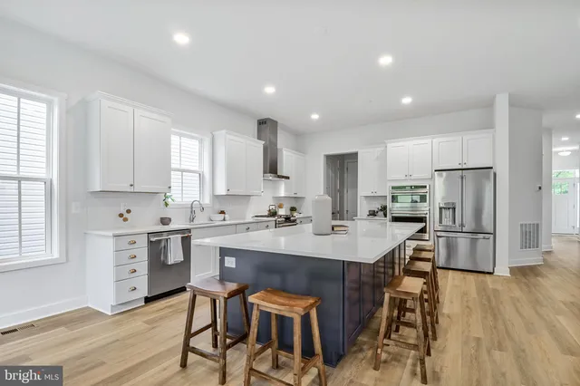 a kitchen with stainless steel appliances a table and chairs in it