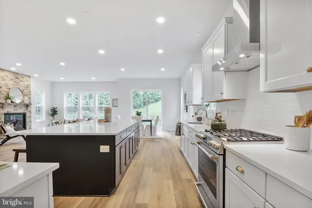 a kitchen with stainless steel appliances a sink a stove a refrigerator cabinets and living room view