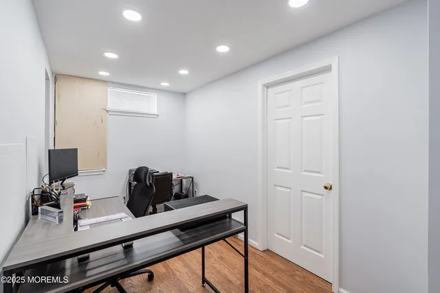 a hallway with a computer on a desk and chair with wooden floor